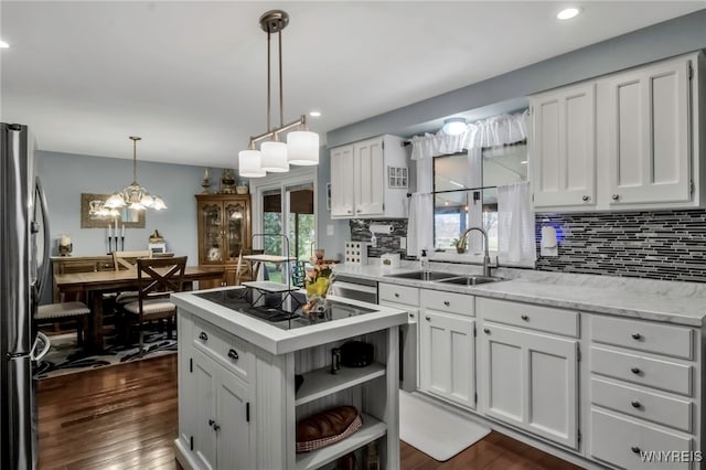kitchen with white cabinetry, black electric cooktop, a sink, and freestanding refrigerator