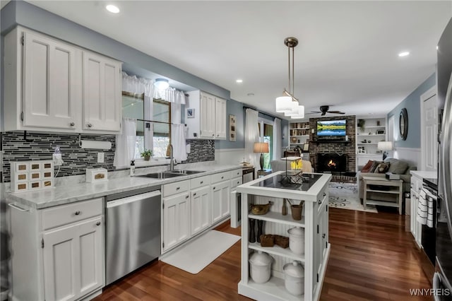 kitchen with a sink, a fireplace, a kitchen island, dishwasher, and open floor plan