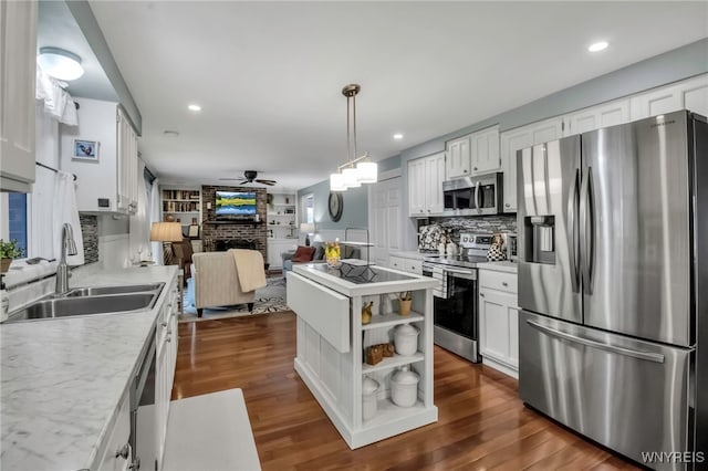 kitchen with appliances with stainless steel finishes, light countertops, white cabinets, ceiling fan, and a sink