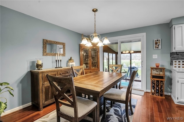 dining space featuring baseboards, wood finished floors, and a notable chandelier