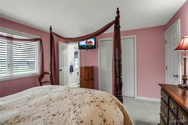 bedroom featuring baseboards, two closets, and light colored carpet