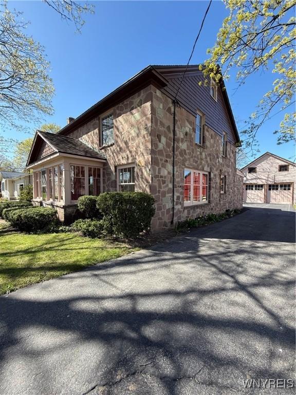 view of side of property with a garage, a yard, and stone siding