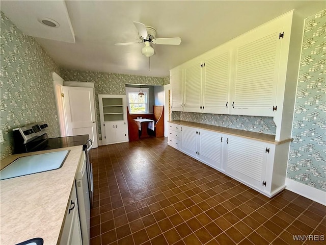 kitchen with wallpapered walls, light countertops, baseboards, stainless steel electric stove, and a ceiling fan