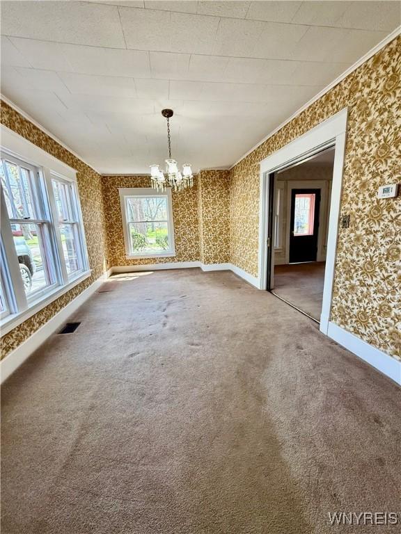 unfurnished dining area with a chandelier, visible vents, wallpapered walls, carpet floors, and plenty of natural light