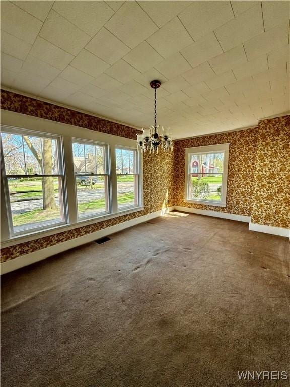 unfurnished dining area with a chandelier, visible vents, baseboards, wallpapered walls, and carpet floors