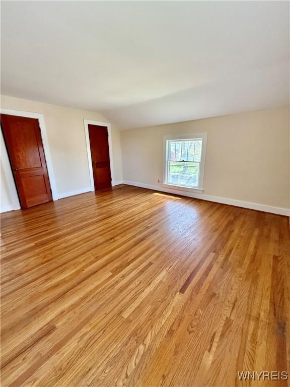 unfurnished room with baseboards and light wood-type flooring