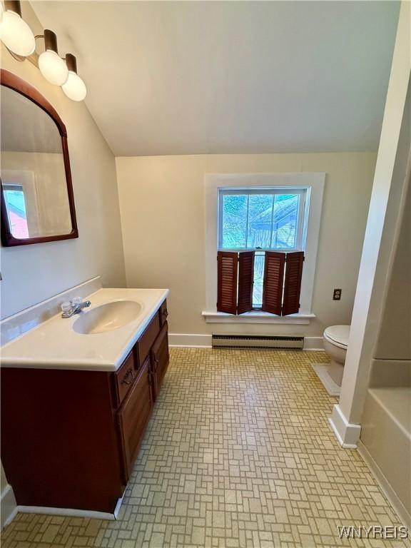 full bath with vanity, brick patterned floor, toilet, baseboards, and baseboard heating