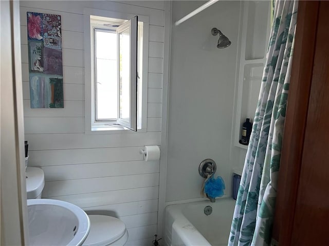 bathroom with toilet, shower / bath combo with shower curtain, and a healthy amount of sunlight