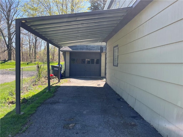 view of vehicle parking featuring fence and aphalt driveway