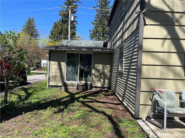 view of side of property with roof with shingles