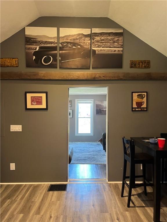 hall with lofted ceiling and wood finished floors