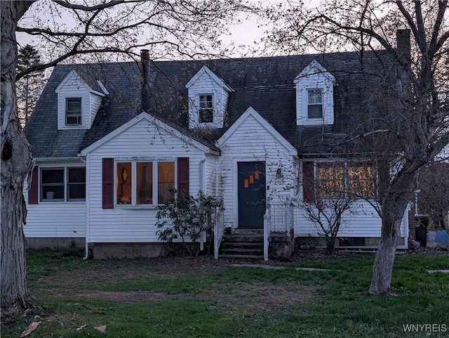 cape cod home featuring a chimney and a front yard