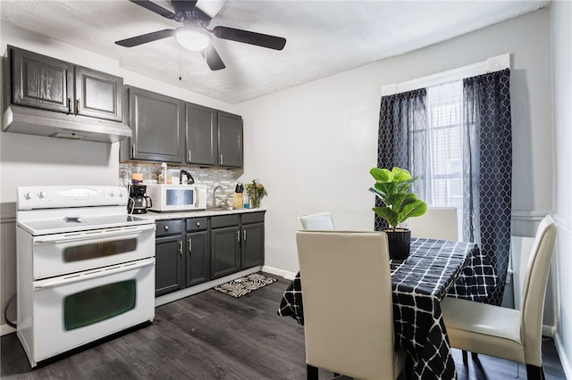 kitchen with under cabinet range hood, dark wood-type flooring, tasteful backsplash, a ceiling fan, and white appliances