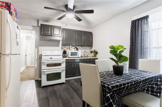 kitchen with dark wood-style flooring, under cabinet range hood, white appliances, tasteful backsplash, and light countertops