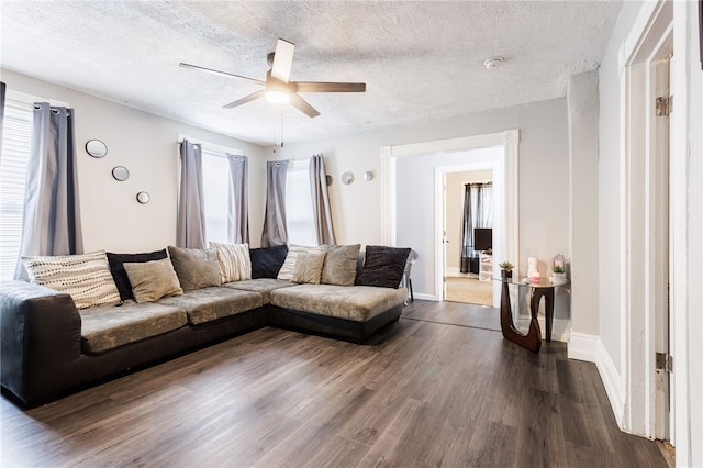 living area with dark wood-style floors, a ceiling fan, a textured ceiling, and baseboards
