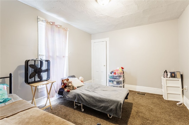 bedroom featuring a textured ceiling, visible vents, carpet floors, and baseboards