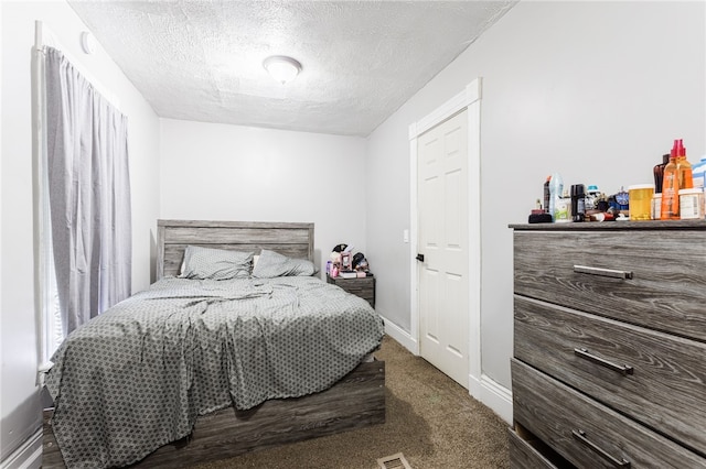 carpeted bedroom featuring a textured ceiling and baseboards