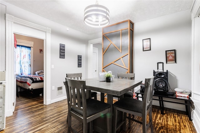 dining room featuring baseboards, visible vents, wood finished floors, and a notable chandelier