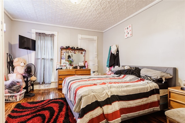 bedroom with ornamental molding, an ornate ceiling, and wood finished floors