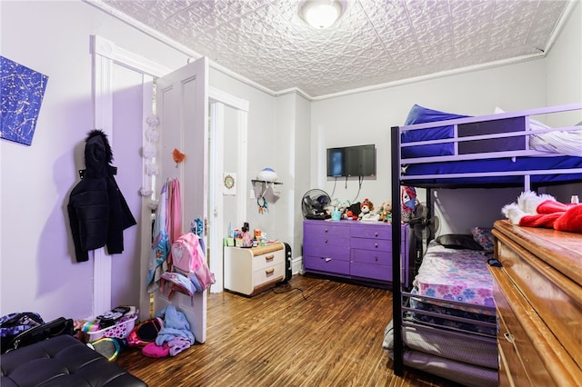 bedroom with wood finished floors, ornamental molding, and an ornate ceiling