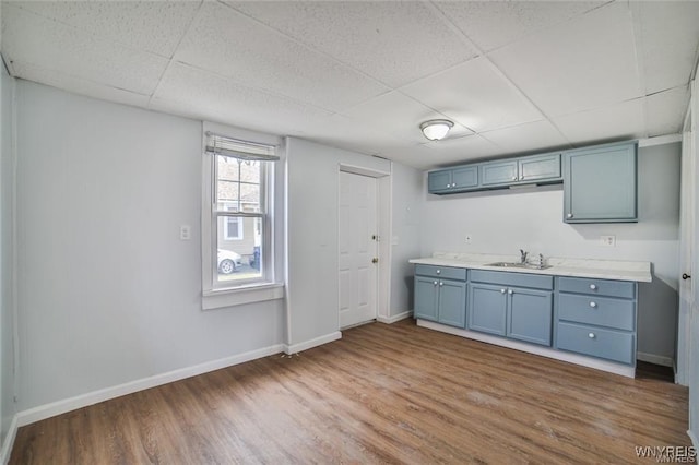 1001 Garden Ave, Niagara Falls, NY 14305 - kitchen featuring a paneled ceiling, wood finished floors, blue cabinets, and a sink