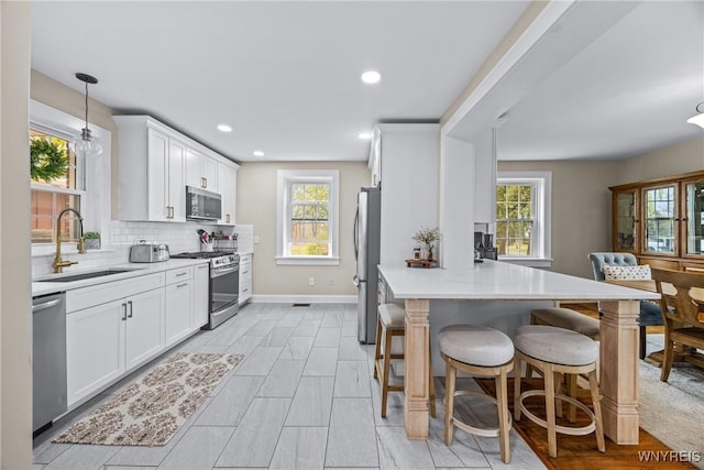 kitchen with a healthy amount of sunlight, a peninsula, appliances with stainless steel finishes, and a sink