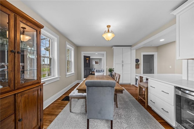 dining space with dark wood-style floors, recessed lighting, baseboards, and beverage cooler