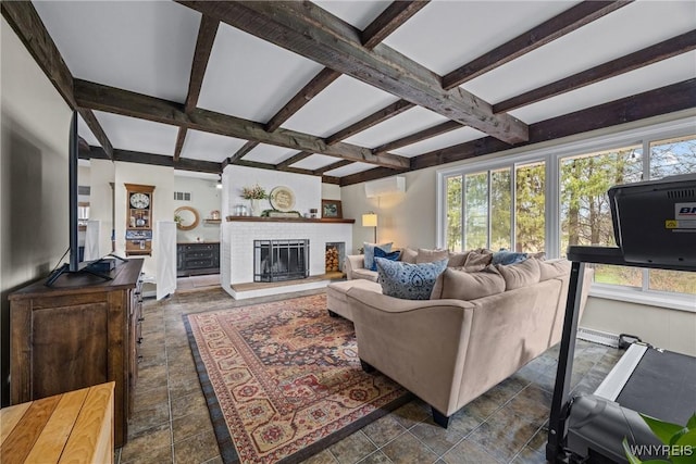 living area featuring beamed ceiling, a wall unit AC, a fireplace, coffered ceiling, and stone finish floor