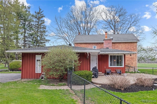 view of front of house with a front yard, a chimney, board and batten siding, and fence