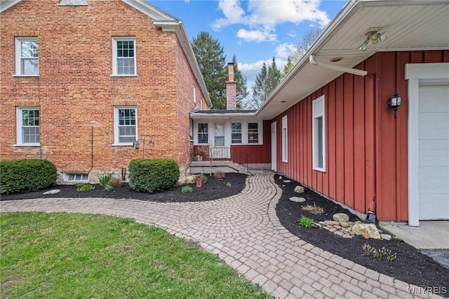 view of home's exterior with brick siding, board and batten siding, and a chimney
