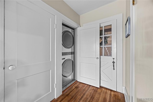 clothes washing area featuring stacked washer and dryer, dark wood-style flooring, and laundry area