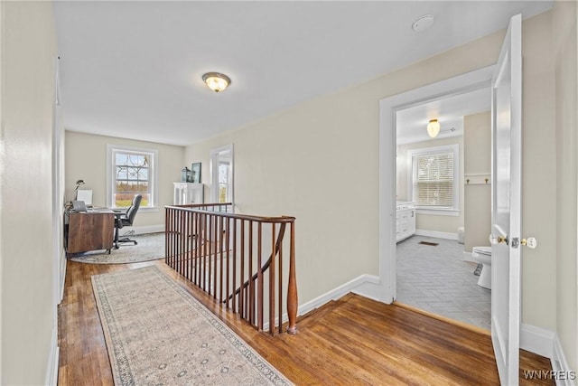 hall featuring an upstairs landing, wood finished floors, and baseboards