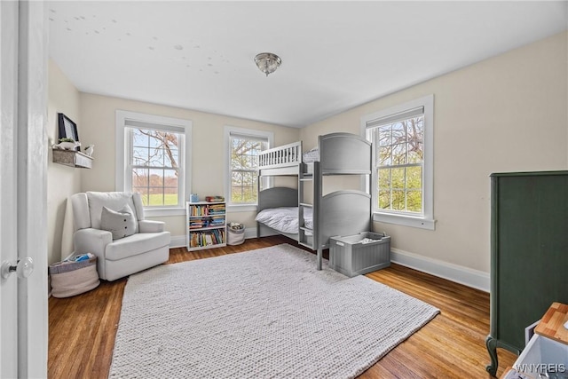 bedroom featuring wood finished floors, baseboards, and multiple windows