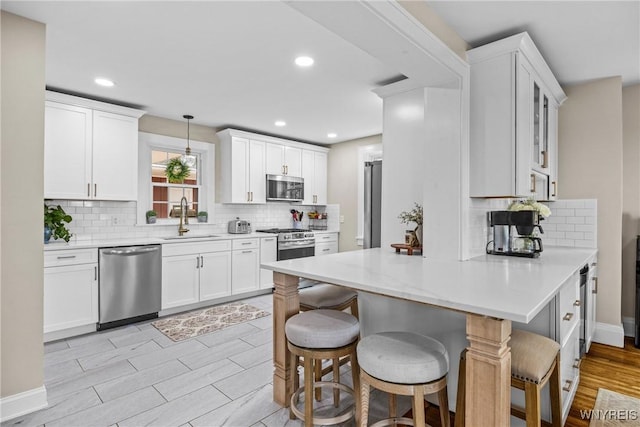 kitchen with tasteful backsplash, stainless steel appliances, a sink, a peninsula, and a kitchen breakfast bar