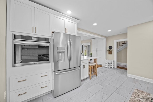 kitchen featuring baseboards, recessed lighting, stainless steel appliances, light countertops, and white cabinetry