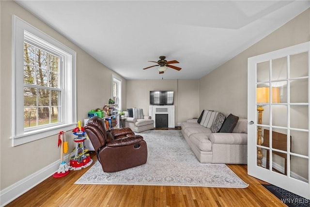 living area with ceiling fan, baseboards, wood finished floors, and a fireplace