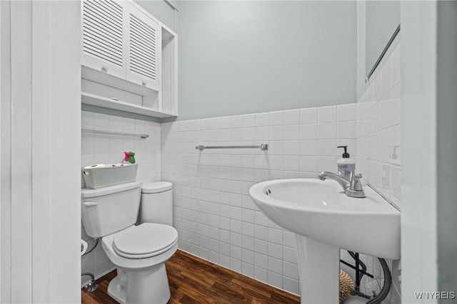 bathroom featuring toilet, a wainscoted wall, tile walls, and wood finished floors