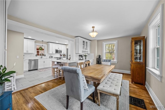 dining area with baseboards, light wood-type flooring, visible vents, and recessed lighting