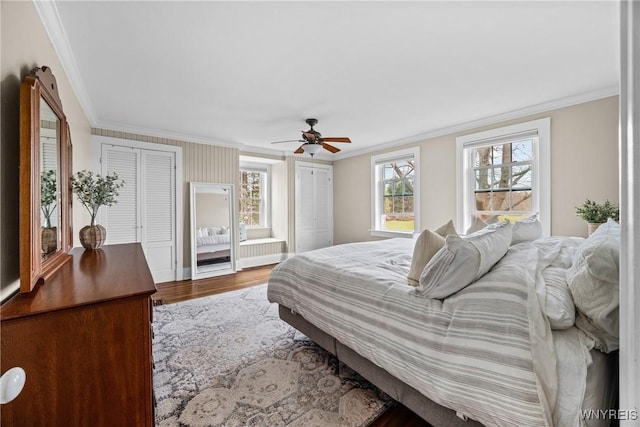bedroom with wood finished floors, two closets, crown molding, and a ceiling fan