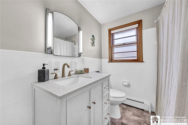 bathroom featuring tile walls, vanity, a wainscoted wall, a baseboard heating unit, and toilet