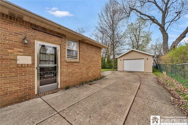view of side of home featuring fence, brick siding, a garage, an outdoor structure, and driveway