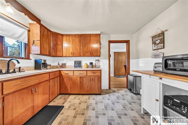 kitchen featuring light countertops, brown cabinetry, and a sink