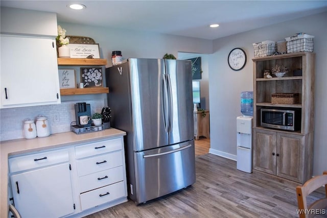 kitchen with white cabinets, open shelves, appliances with stainless steel finishes, and light wood-style floors