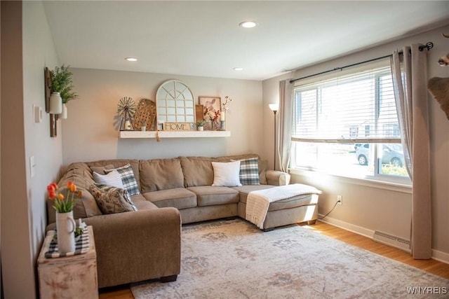 living area with baseboards, wood finished floors, a healthy amount of sunlight, and visible vents