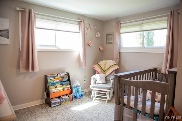 carpeted bedroom with baseboards and a crib