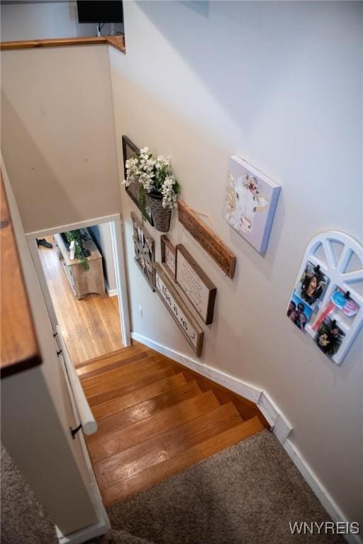 staircase with baseboards and wood finished floors