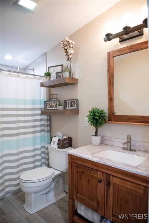 bathroom with vanity, a shower with shower curtain, wood finished floors, and toilet