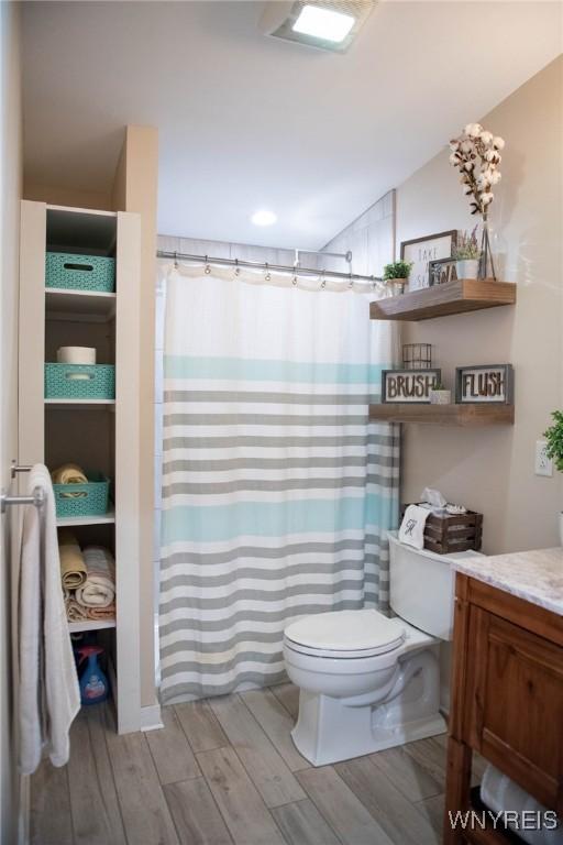 full bath with vanity, a shower with shower curtain, wood finished floors, and toilet