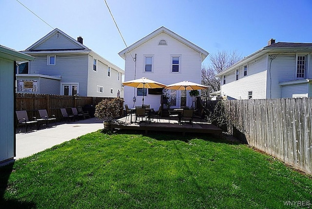 rear view of property with a lawn, a patio, a wooden deck, and a fenced backyard