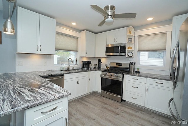 kitchen with backsplash, a sink, white cabinets, dark stone counters, and stainless steel appliances